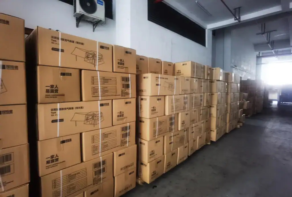 Custom Inflatable Tent Case Study: 45-Day Retail Launch 3 Warehouse interior with stacks of cardboard boxes containing camping tents, neatly arranged and ready for shipment.