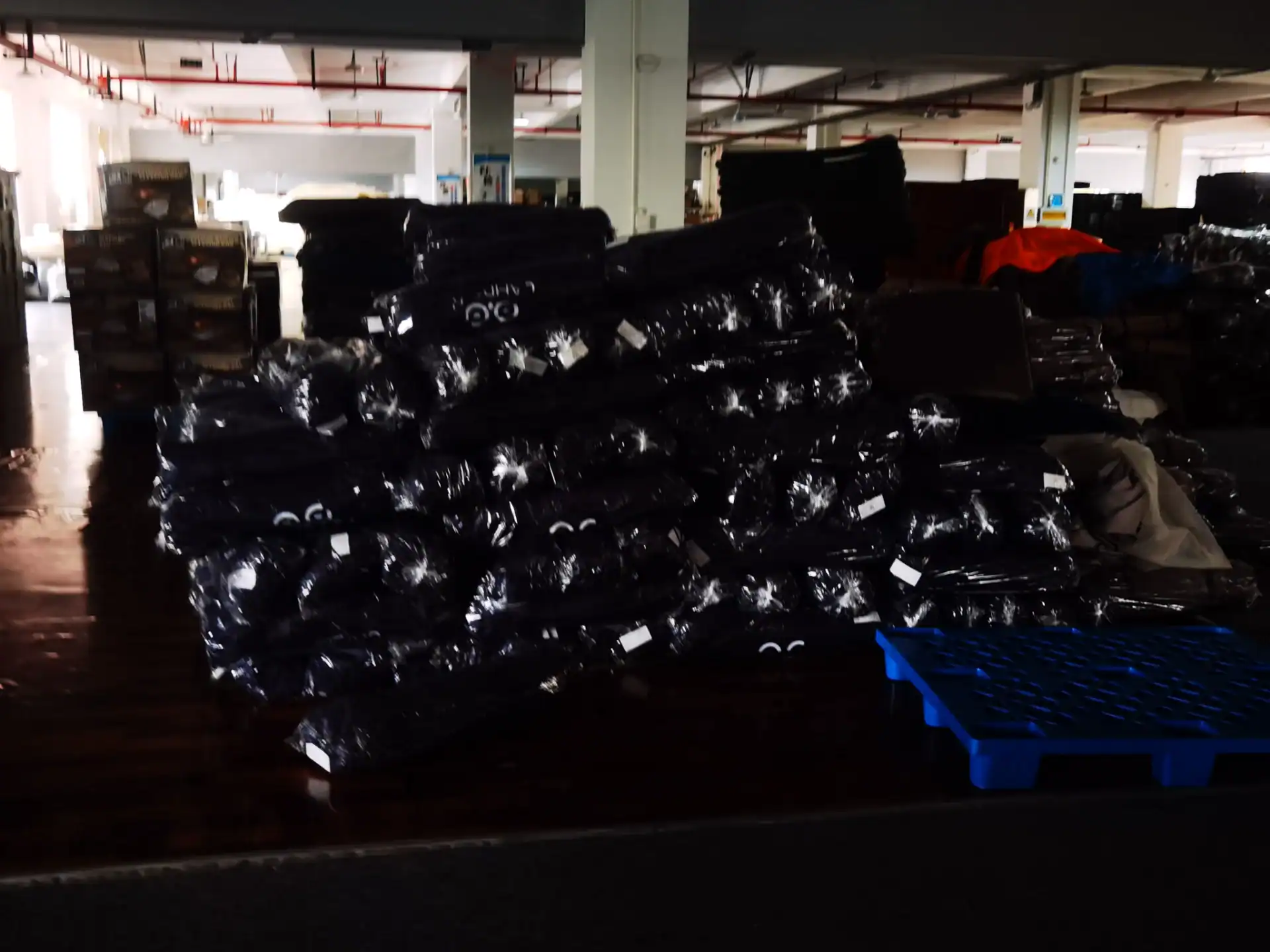 Sourcing Camping Gear: 5 Mistakes That Kill Your Margin 28 Stack of packaged camping gear wrapped in plastic, stored in a warehouse with industrial shelves and bright lighting in the background.