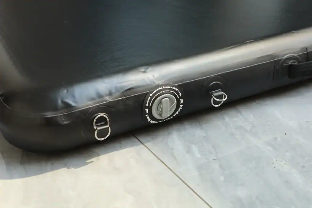 Close-up of a black inflatable boat's valve and D-rings on the floor.