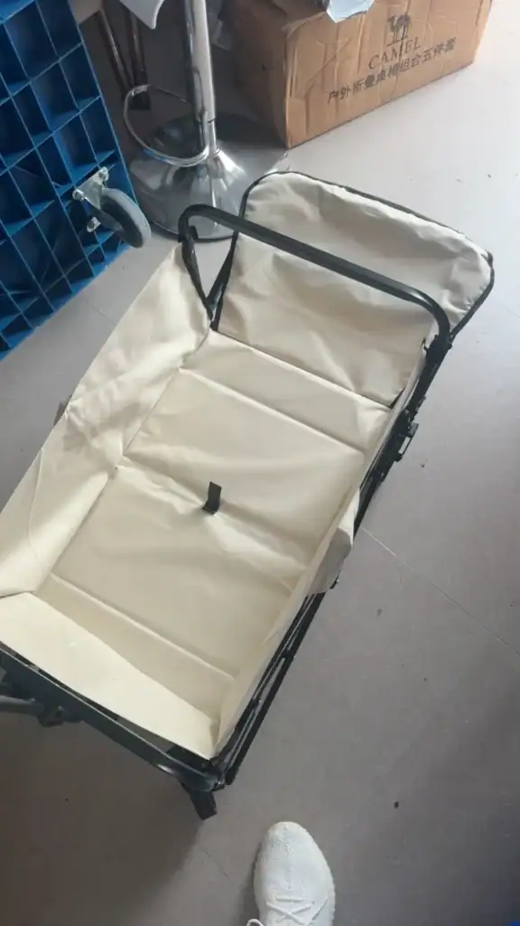 Foldable beige outdoor stroller with black frame on concrete floor.