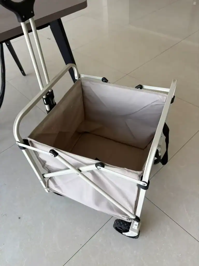 Foldable outdoor utility cart with beige fabric and black wheels.